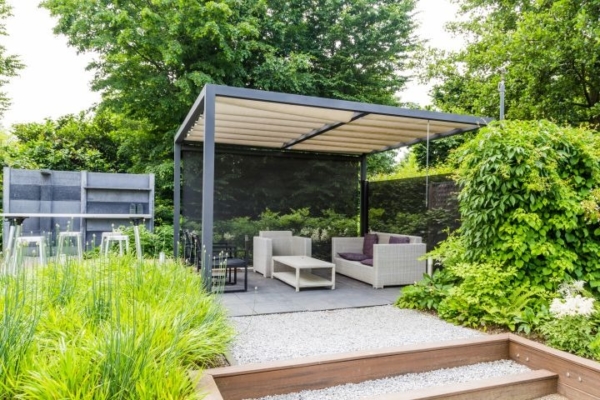 Designer Garten Lounge Ecke mit Überdachung, am Boden Kieselsteine, im Hintergrund Bäume