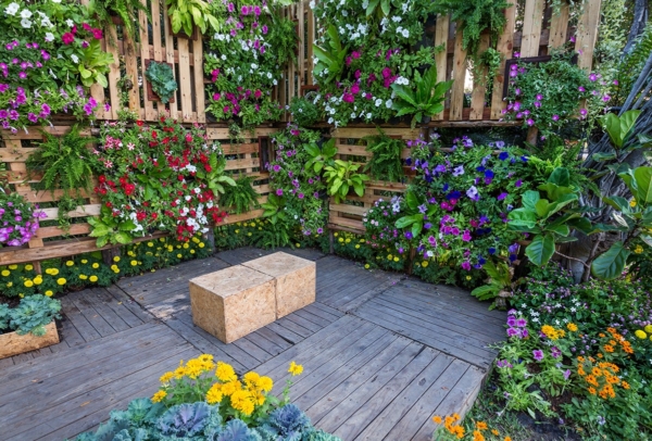 Bild, das Paletten als Mittel zeigt, um vertical gardening zu praktizieren mit vielen Blumen in den Paletten