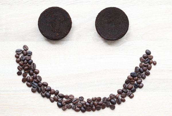 Smiley aufgelegt mit einem Mund aus Kaffeebohnen und zwei Augen aus Kaffeesatz