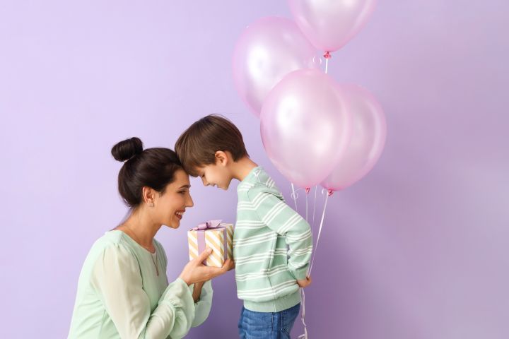 Bub schenkt seiner Mama ein Geschenk und Luftbalone