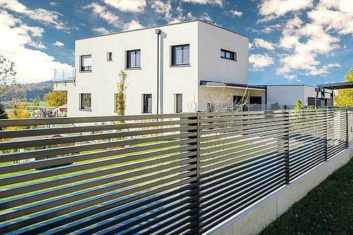 Lamellenzaun in anthrazit, Modell Linea von GUARDI, Gewinner-Zaun des Infinity Design Award, vor einem weißen, modernen Haus