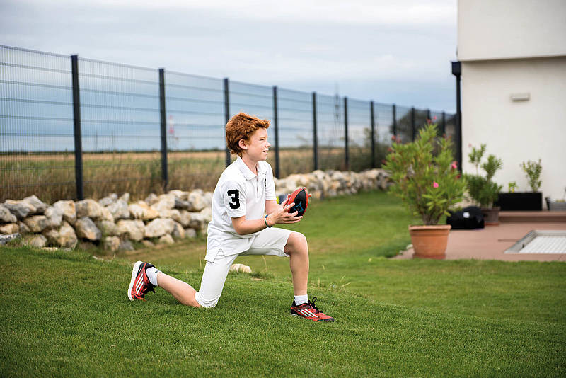 Ein Junge spielt mit einem Football vor einer Doppelstabmatte in anthrazit