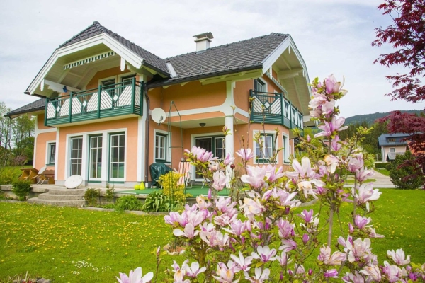 Guardi Modell des Monats Altenmarkt an einem orange gestrichenen Haus, Blumen am Feld vor dem Haus