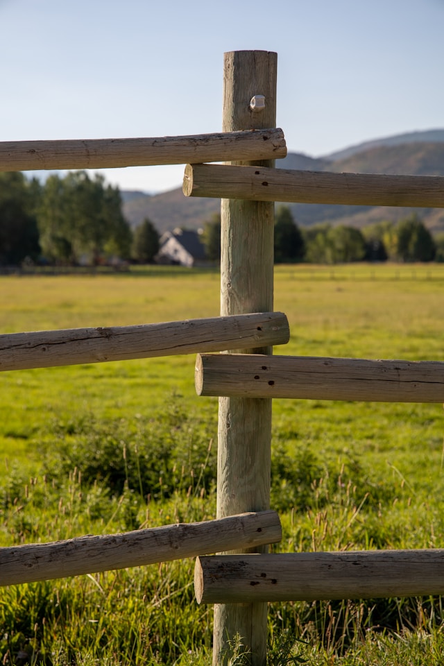 Holzzaun vor einer großen Wiese in einer ländlichen Gegend